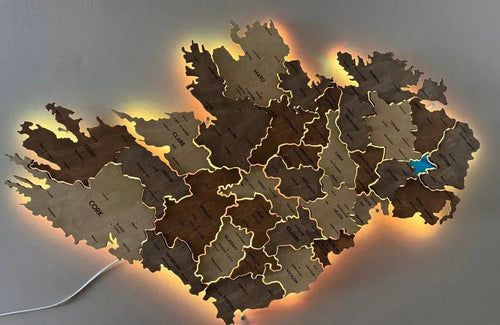 Wooden map of Ireland with counties, illuminated from below, on a gray background.